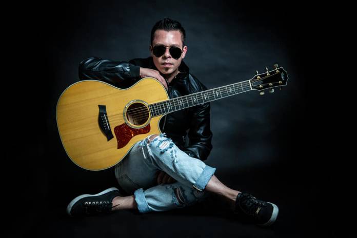 Glenn Sacco performing live on stage with an acoustic guitar